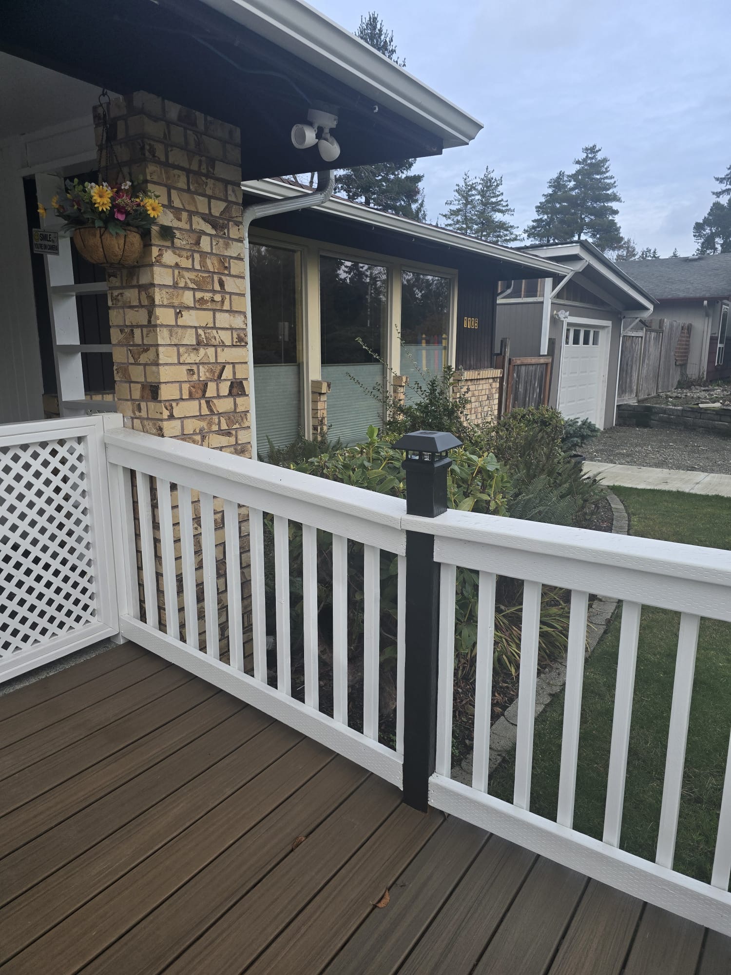Front porch at Gihon Springs Adult Family Home in Tacoma, WA — wood deck, white railing, and hanging flowers